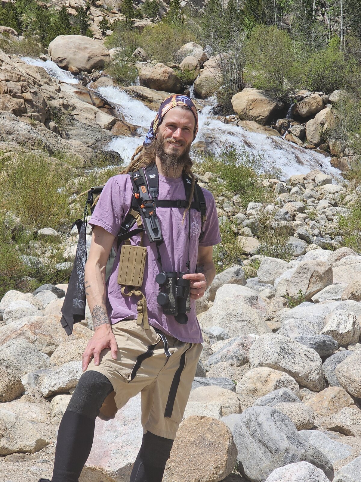 Bradley Thaddeus Harz standing outdoors near a mountain stream